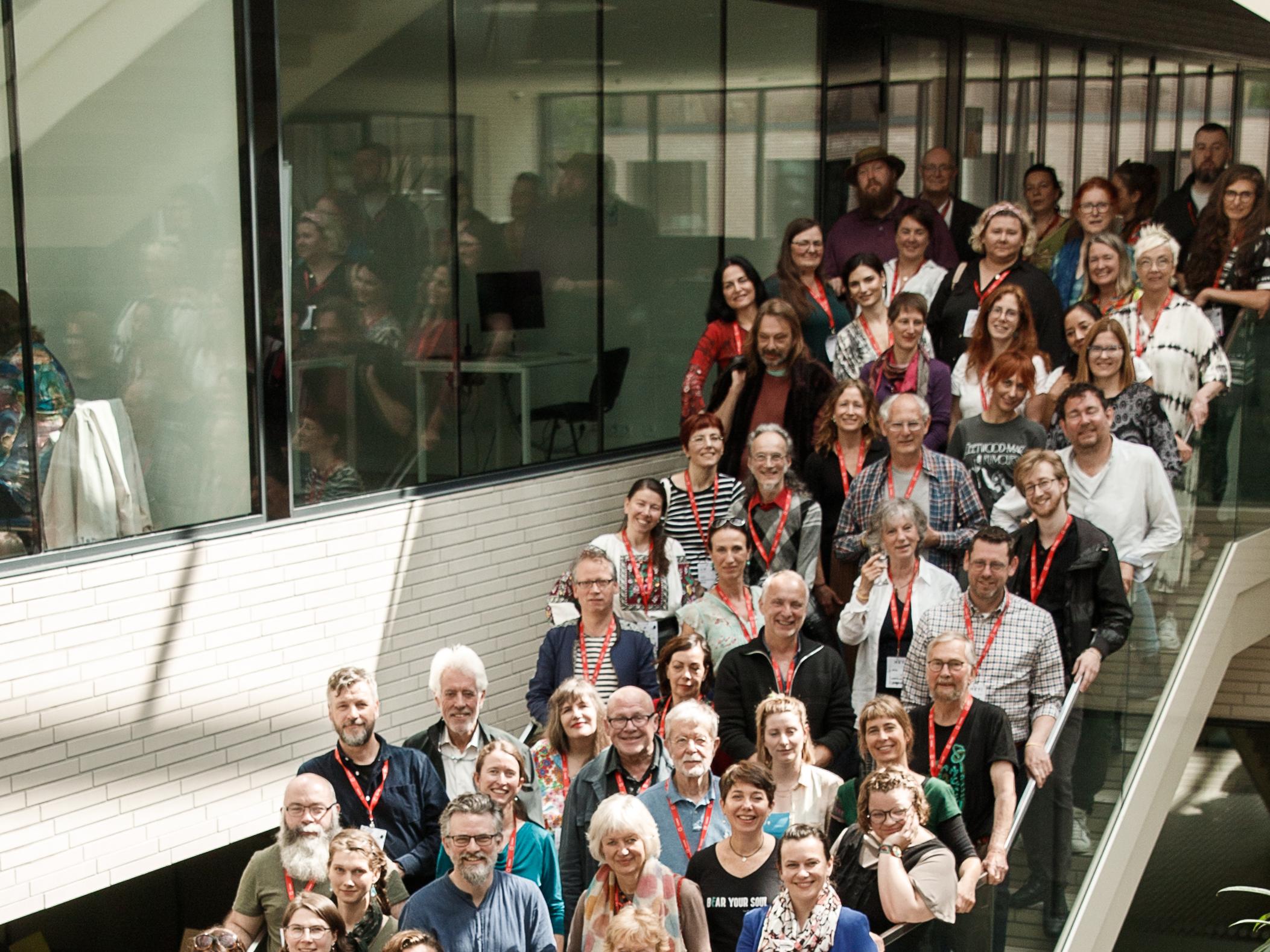 An image of the conference in 2022 with people standing on the stairs in a conference hall