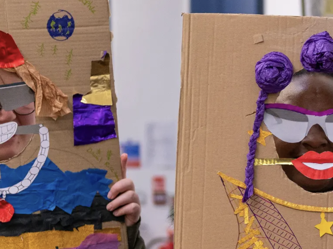 Children holding up drawings and they standing behind them