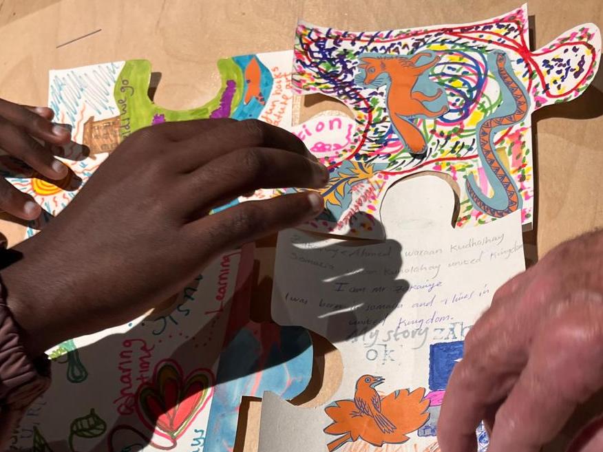 Hands moving images and drawings together on a table