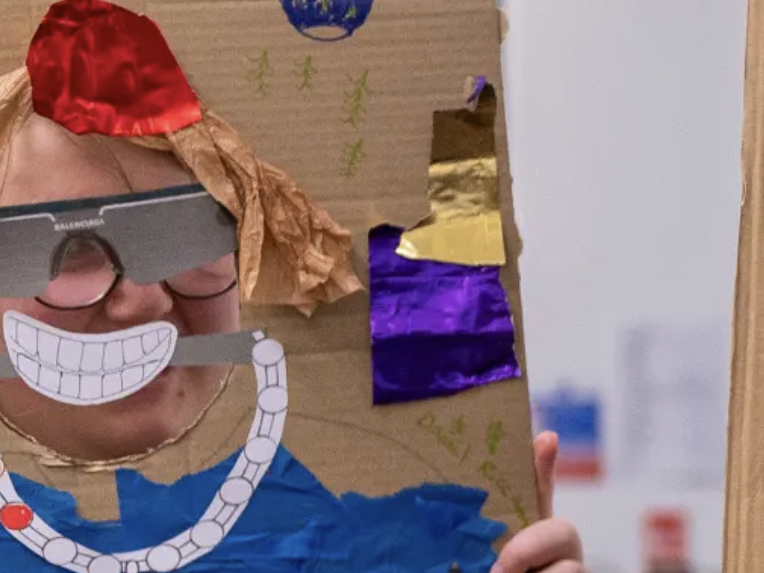 Children holding up drawings and they standing behind them