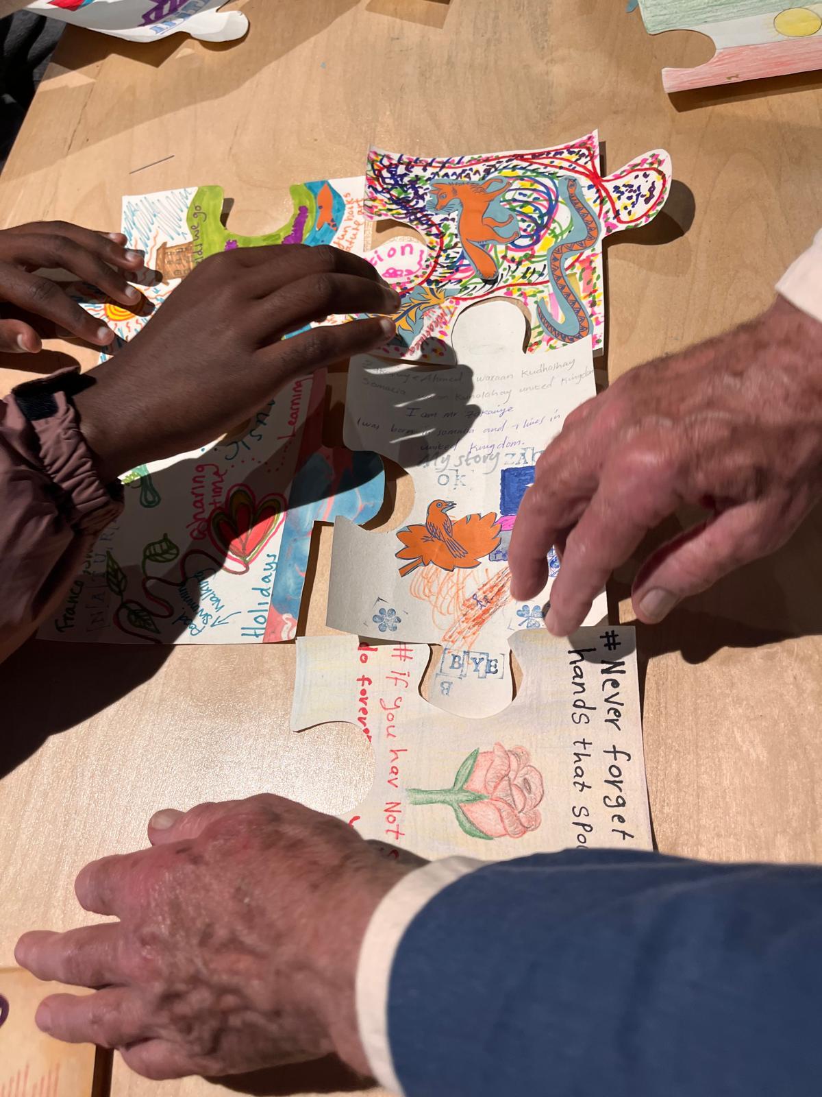 Hands moving images and drawings together on a table
